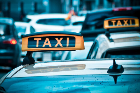 Mehrere Fahrzeuge stehen dicht hintereinander. Von dem vordersten Fahrzeug sieht man nur das Dach. Die zwei Fahrzeuge im Vordergrund sind Taxis, zu erkennen an dem gelben Dachzeichen auf dem Autodach.