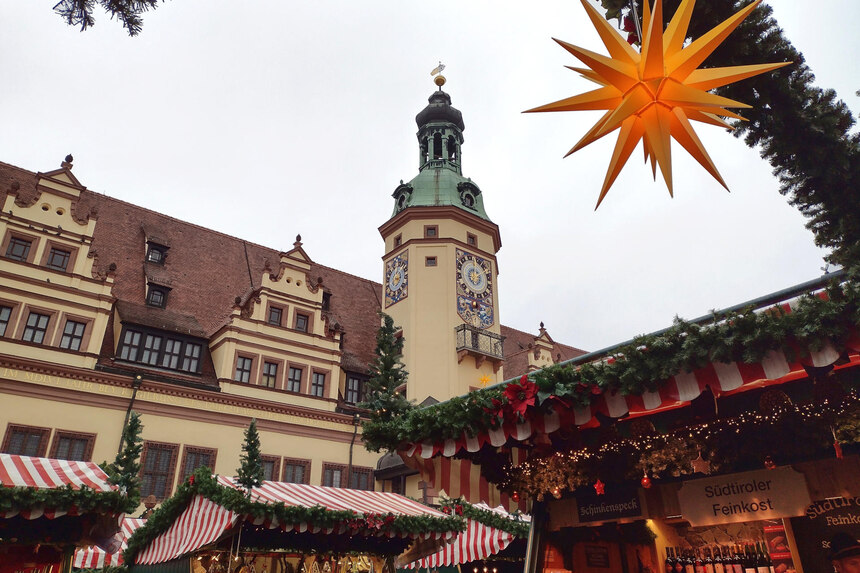 Weihnachtsmarkt Blick vom Weihnachtsmarkt Leipzig zum Rathaus. Im Vordergrund sieht man festlich geschmückte Buden und einen Weihnachtsstern. Der vorderste Stand verkauft Südtiroler Feinkost und Wein.